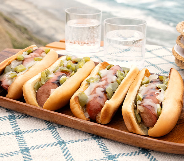 Image of Philly Cheesesteak Grilled Sausages on a tray by the beach.