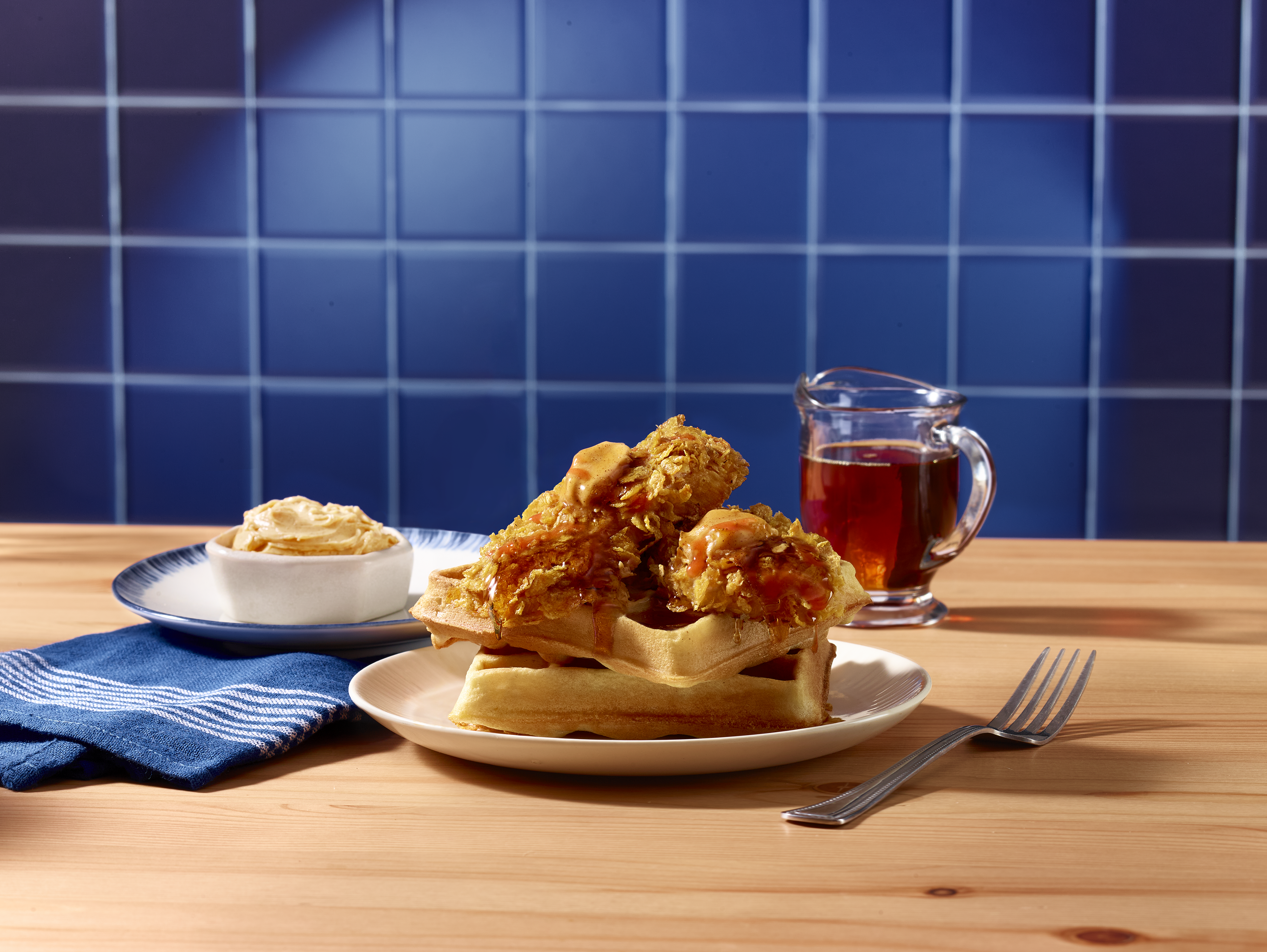 Cornflake crusted turkey tenderloin on a stack of waffles, drizzled with syrup and butter.