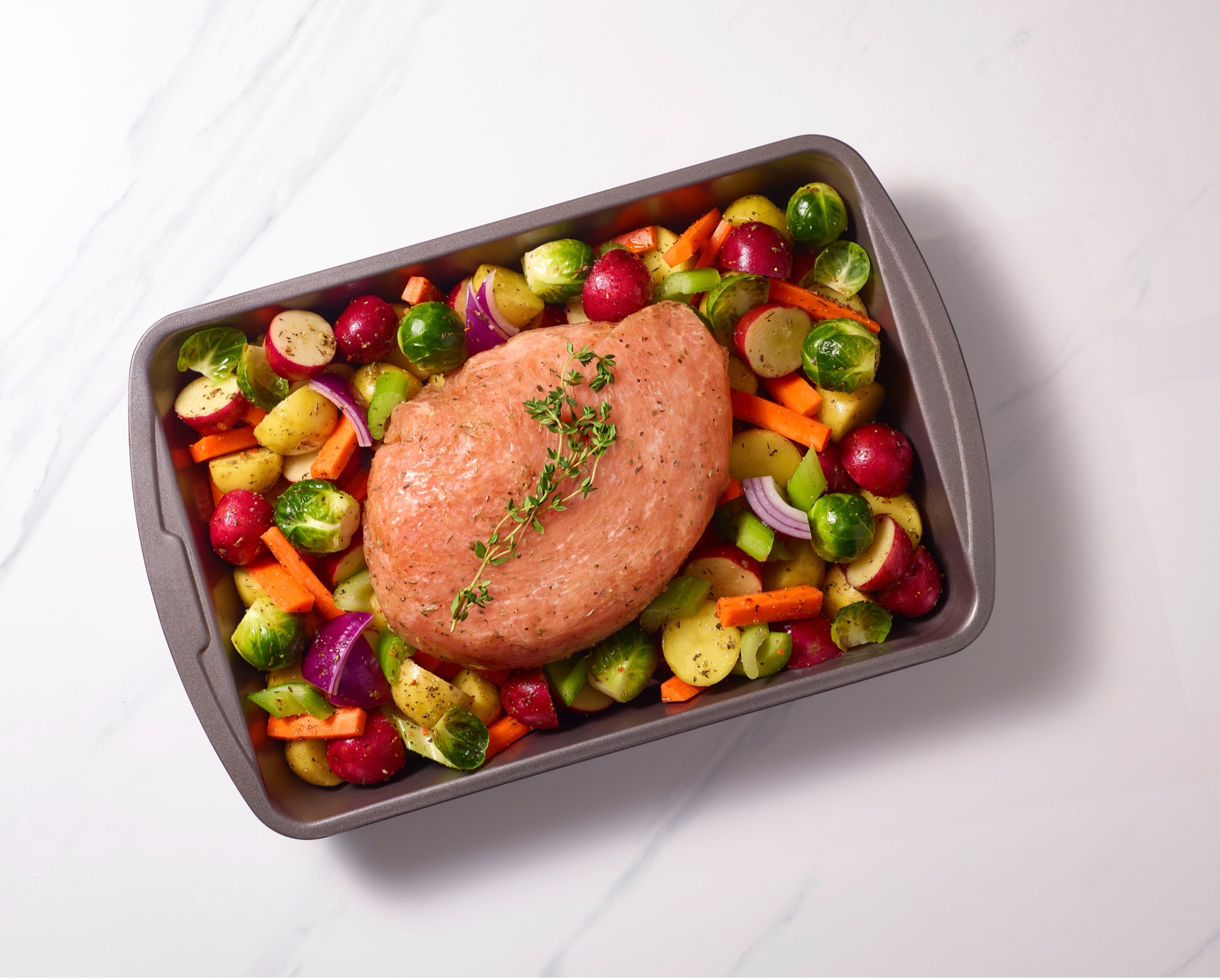 An image of a turkey in a pan with a large number of vegetables around it