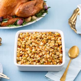 Classic turkey stuffing recipe in a white baking dish, with a roast turkey in the background. 