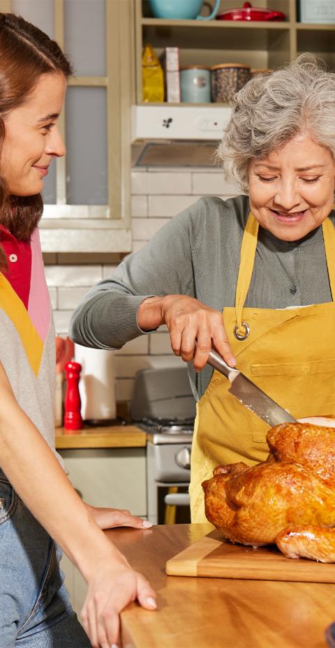 Passing down a family tradition as two generations prepare a roasted turkey for a shared meal.