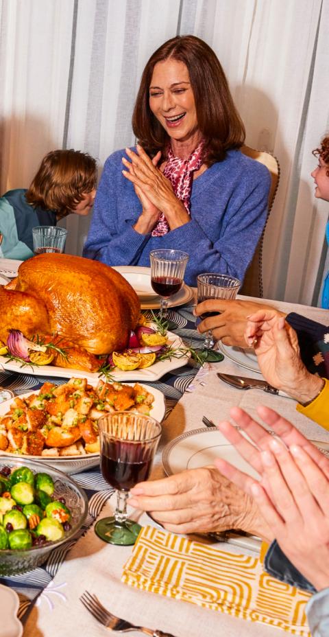 Family smiling, seated around the dinner table over turkey
