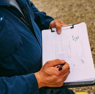 Farmer documenting animal care and well-being records on a clipboard.