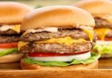 A close-up of a smashburger turkey burger with cheese, onion, lettuce, and tomato.