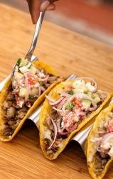 Turkey crispy tacos topped with veggies, onions, and cheese, served on a tray for a tasty meal.