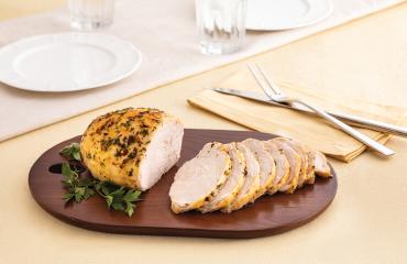 A seasoned Butterball turkey breast recipe, sliced and served on a dark wooden cutting board. 