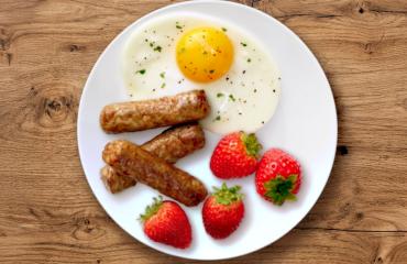 A plate with Butterball turkey breakfast sausage links, one egg and four strawberries.