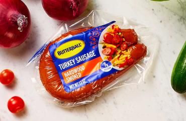 Butterball Hardwood Smoked Turkey sausage on a counter next to a variety of vegetables.
