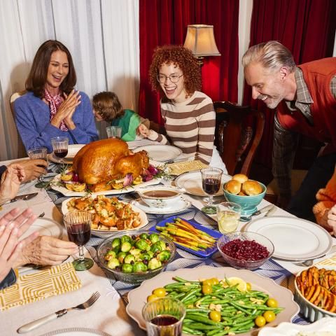 Large family gathering around a table for Thanksgiving dinner.