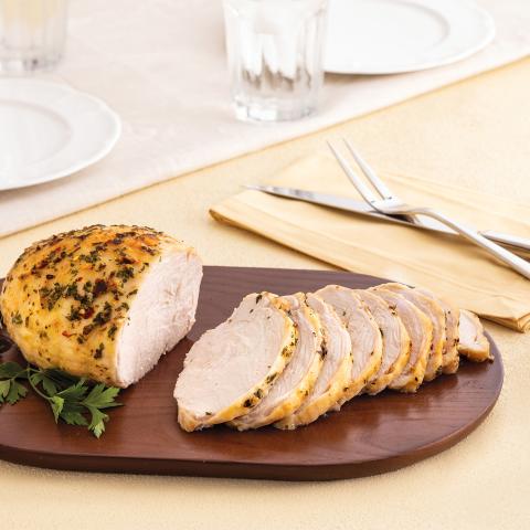 A seasoned Butterball turkey breast recipe, sliced and served on a dark wooden cutting board. 