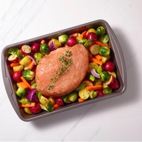 An image of a turkey in a pan with a large number of vegetables around it
