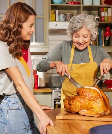Passing down a family tradition as two generations prepare a roasted turkey for a shared meal.