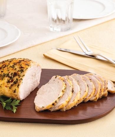 A seasoned Butterball turkey breast recipe, sliced and served on a dark wooden cutting board. 