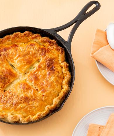 Leftover turkey recipe: a golden-brown pot pie with a flaky crust in a cast iron skillet. 