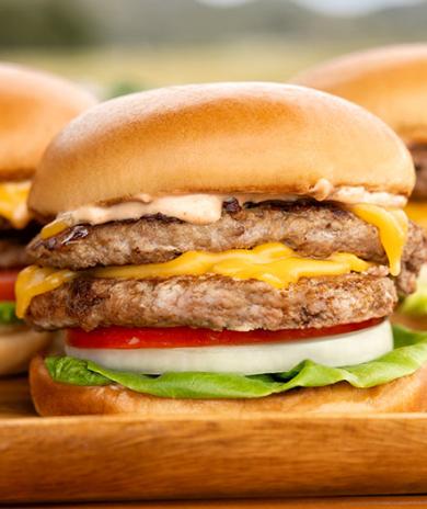 Stacked turkey cheeseburgers with lettuce, tomato, onion, and melted cheese on a soft bun.