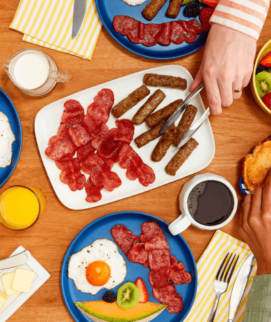 A table with several plates filled with breakfast foods.