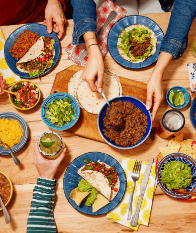 Overhead view of friends enjoying a taco night with colorful toppings.