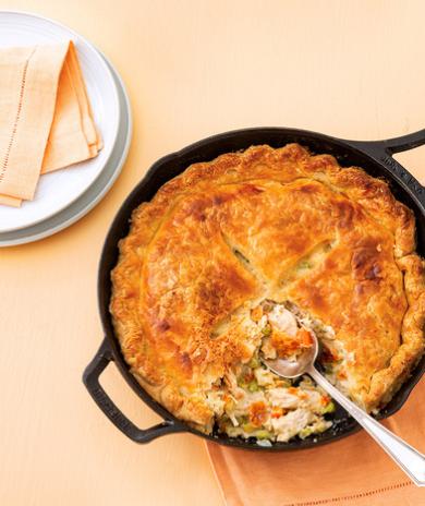 Leftover turkey recipe: a golden-brown pot pie with a flaky crust in a cast iron skillet. 
