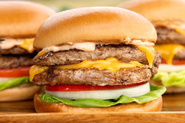 A close-up of a smashburger turkey burger with cheese, onion, lettuce, and tomato.