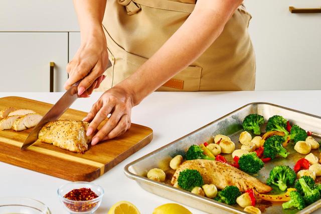 A person slices a Butterball turkey tenderloin with a chef's knife on a cutting board.