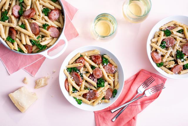 Lemon broccolini pasta with turkey sausage, served in bowls on a pink table setting.